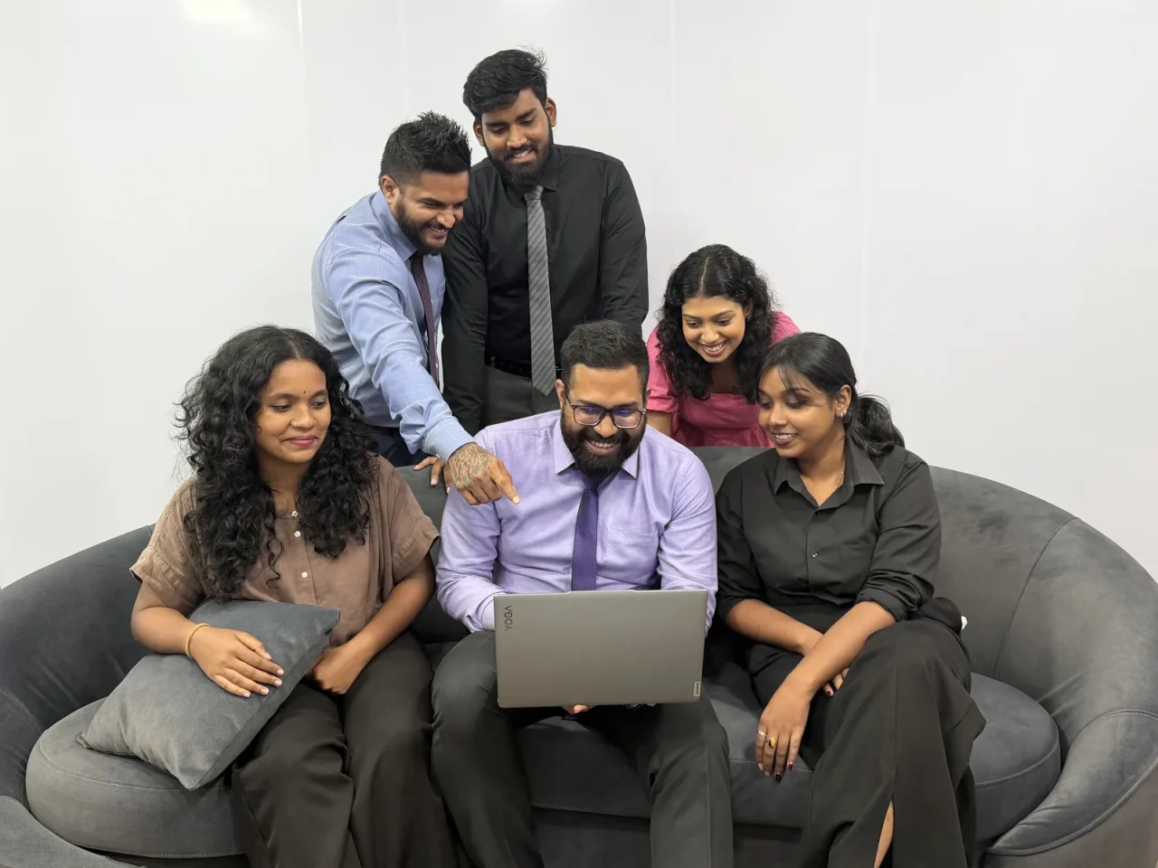 A group of colleagues gathered on a couch around a laptop
