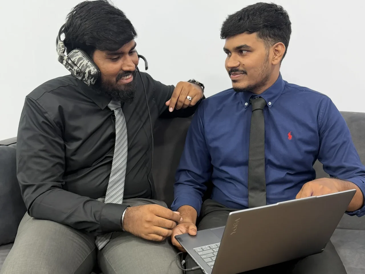 Two colleagues working together on a laptop on the office couch