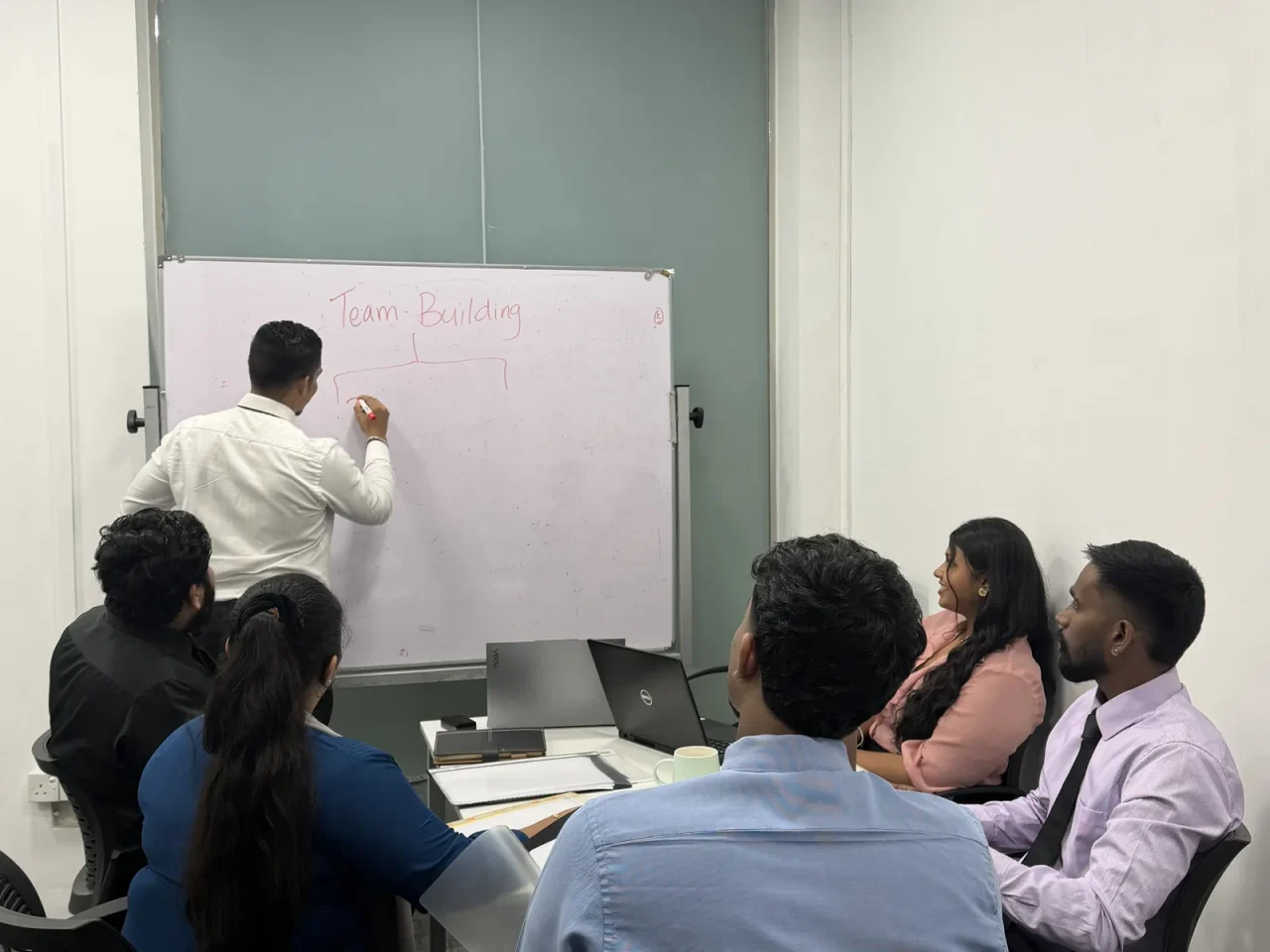 A team meeting in progress around the whiteboard in the meeting room