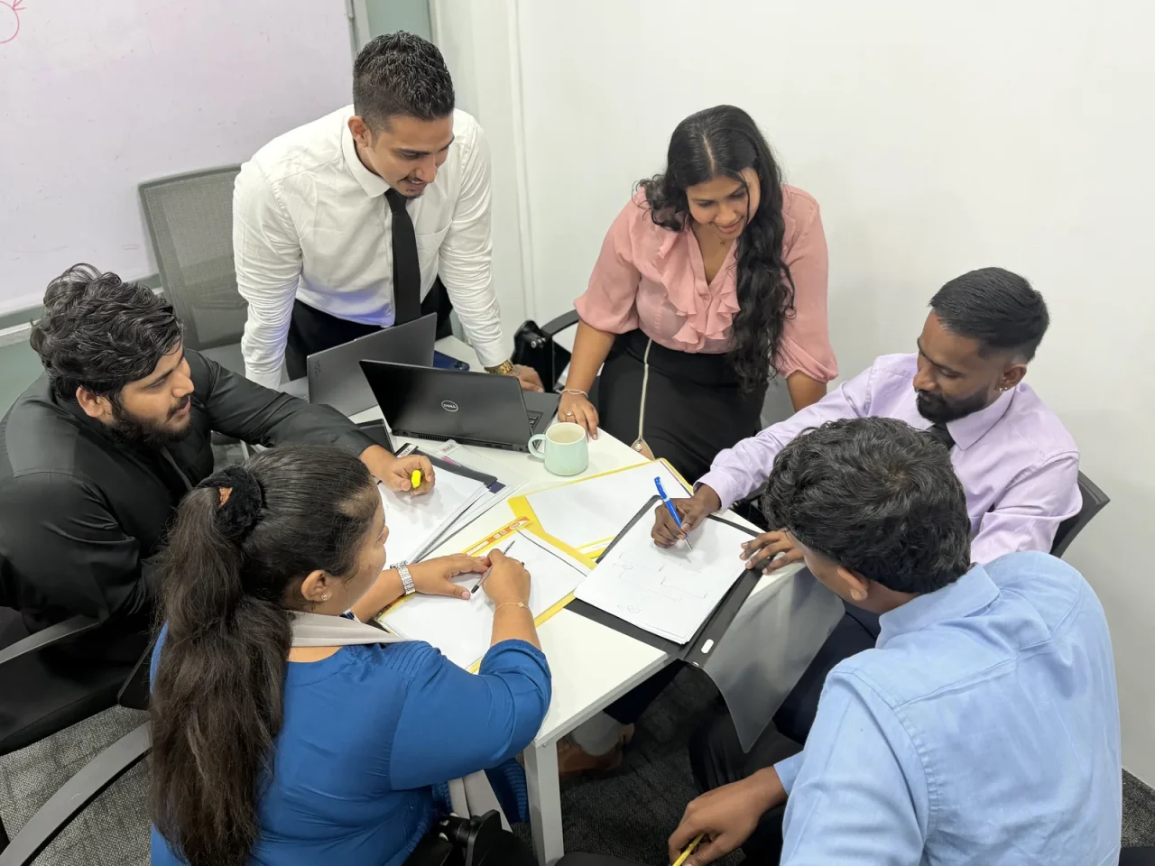 Colleagues working together around a table with laptops and notebooks